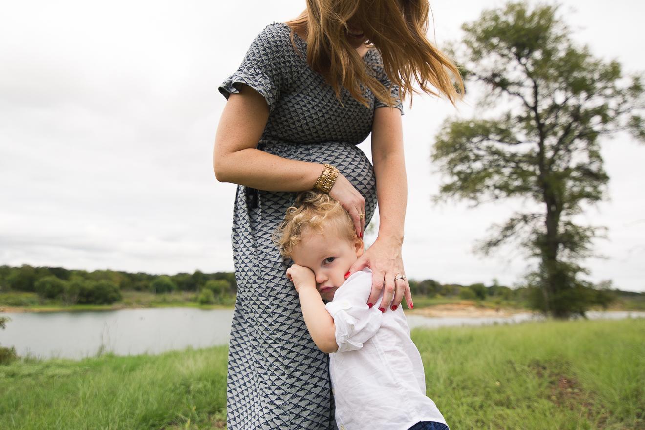 Professional family photography of a Boy snuggling pregnant mom in a field near Flower Mound Southlake Trophy Club Texas