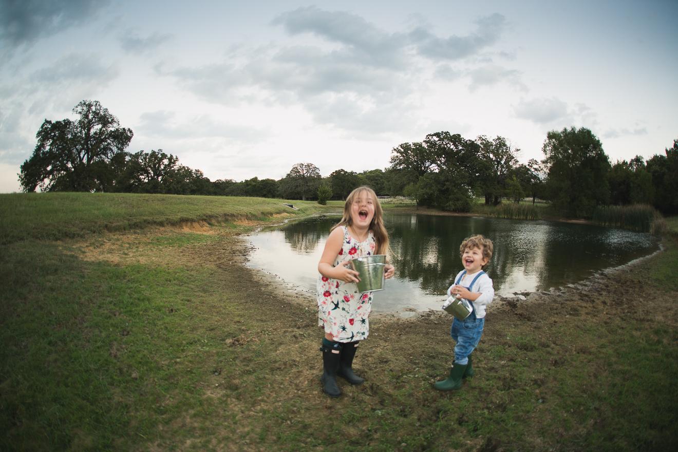 Siblings playing near a pond on a family farm by best award winning photographer in Dallas Fort Worth Texas