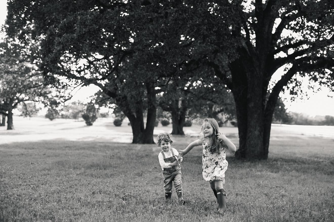 Brother and sister playing in field by fine art portrait photojournalistic photographer
