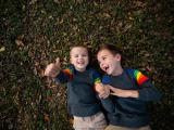 Two happy boys laying in leaves during a family lifestyle photoshoot in Trophy Club Keller Flower Mound Texas with international award winning photographer
